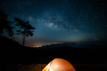 nature traveling with orange camping tent on mountain with milky way background