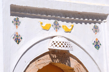 Tunezja Djerbahood, 04 kwiecień 2024, ozdobne nadproże nad wejsciem do domu z motywem żółtych ryb - obrazy, fototapety, plakaty