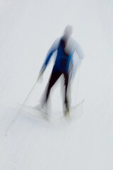 Intentional camera movement (ICM) image of cross-courtry skier going up a hill created by motion blur.