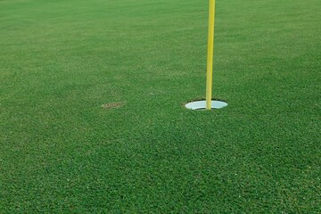 Obraz premium Hole with flagpole in golf course on green grass field.