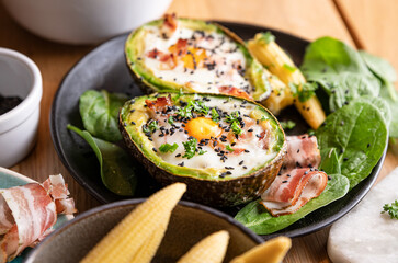 Cooking Avocado with Egg and Bacon. The girl prepares a healthy meal, close-up of her hands and products in the frame. Breakfast for complete nutrition
