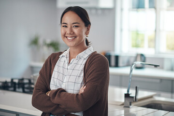 Asian woman, smile and arms crossed, excited for real estate or purchasing house with kitchen in...