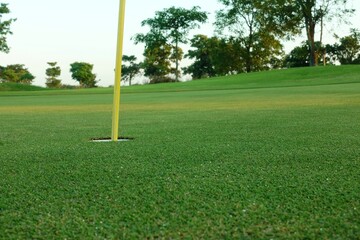Obraz premium Hole with flagpole in golf course on green grass field.