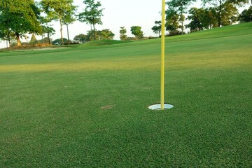 Obraz premium Hole with flagpole in golf course on green grass field.