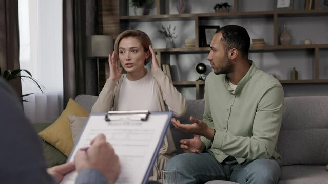 Multiracial quarrel between husband and wife at a session with a psychotherapist. A visit to a family psychologist for a married couple. A doctor consults an unhappy married couple. Help psychologist.