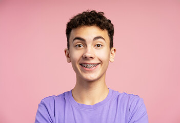 Excited, smiling boy with braces wearing casual purple t shirt looking at camera - obrazy, fototapety, plakaty