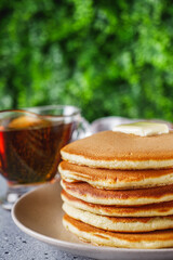 fresh tasty pancakes with maple syrup on a light stone background