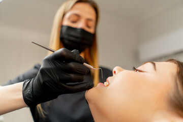 close-up in the dental office of a girl dentist examines the oral cavity of a girl patient