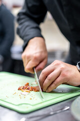 Focused chef skillfully chopping ingredients on a green cutting board in a professional kitchen, showcasing the art of culinary precision