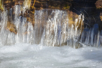 A tranquil cascade of water flows over natural rocks, creating a blurred, silky effect.