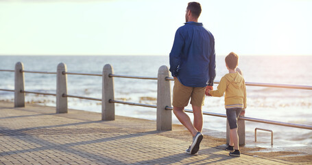 Father, boy and holding hands on promenade, beach or walking on vacation with love, care and...