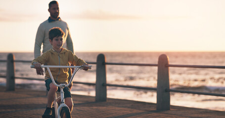 Father, boy and bike for learning at beach, promenade and sunset on vacation with care, love and...