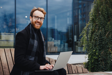 Successful businessman on the background of the business center. Red-haired young guy, in a stylish...