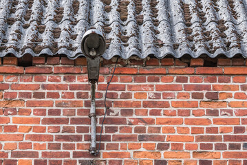 STREET LAMP - Very old and destroyed lantern on an old brick building with an asbestos roof
