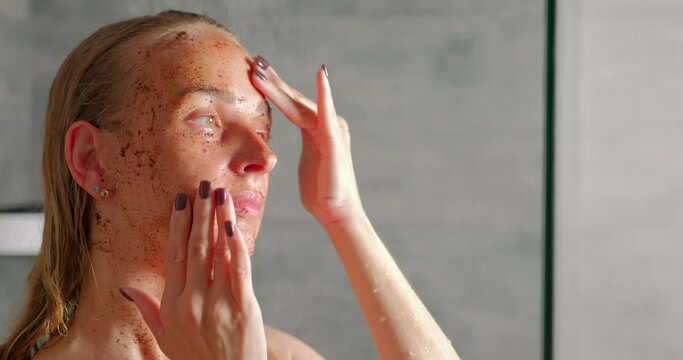 A young woman massages her face with a scrub