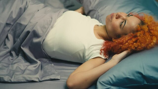 Irritated young woman covering ears with pillow, noisy city area, lack of sleep