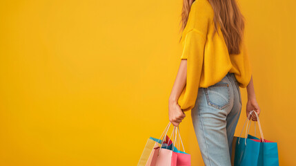 Woman with shopping bags on yellow background closeup.