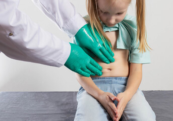 The hands of a therapist doctor palpate the abdomen of a little seven-year-old girl for organ soreness. Inflammation of the abdominal organs, dyspepsia and pain in the intestines, close-up - 787160647
