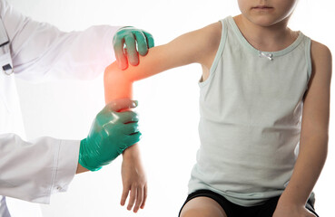 The hands of a traumatologist doctor in green medical gloves examine the girl s damaged elbow...