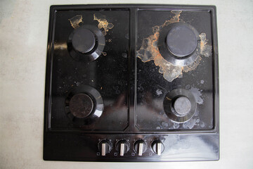 Carbon deposits and dirt on a black built-in gas stove. Cleaning kitchen appliances, close-up - 787161256