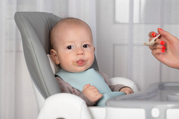 The first feeding with fruit puree for a baby boy who is 6 months old, close-up. Copy space for text - 787161476