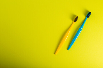 Yellow and blue toothbrush with charcoal coating on a yellow background. The concept of dental and...
