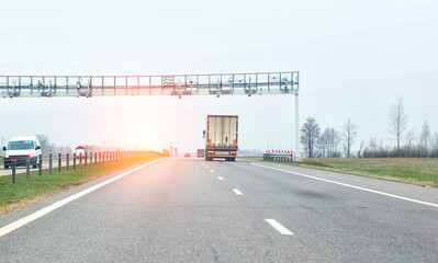 a truck passes through a toll frame against the backdrop of the sun and car traffic. Concept map of toll roads in the country, copy space for text, business