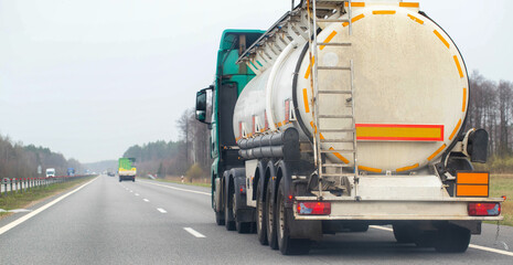 A truck with a semi-trailer tanker transports dangerous cargo along the highway - liquefied gas. Logistics of dangerous goods. Copy space for text