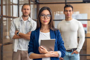 Group of young corporate professionals standing together and looking at camera. Multiracial business people standing in office. Coworking, job in finances business IT