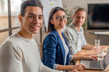 Happy group of businesspeople during business meeting. Colleagues looking at camera and smiling while sitting in boardroom in office