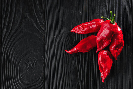fresh red extra hot bhut jholokiya pepper on black wooden rustic background