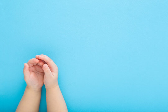 Baby boy opened palms on light blue table background. Pastel color. Closeup. Point of view shot. Empty place for text. Top down view.