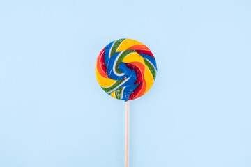 Multicolored rainbow swirled candy on stick. Colorful lollipop on a bright background, LGBT flag, children's day, summer holiday concept