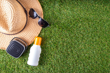 Spring, summer picnic, outdoor recreation background. A woman's straw hat, a picnic blanket or tablecloth, sunscreen spray, an apple on a background of green artificial grass or lawn, copy space - 787167021
