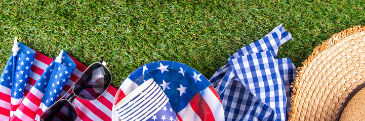 July 4, Independence Day traditional American picnic background. Plates, glasses, USA flags on green lawn or meadow grass, with blanket or tablecloth for picnic, sunglasses, copy space top view - 787167227
