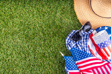 July 4, Independence Day traditional American picnic background. Plates, glasses, USA flags on green lawn or meadow grass, with blanket or tablecloth for picnic, sunglasses, copy space top view - 787167255