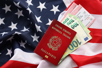 Italian passport and money on United States national flag background close up. Tourism and...
