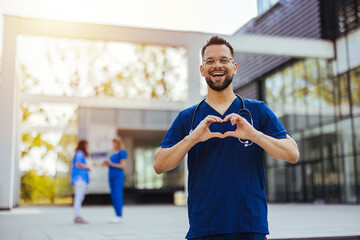Closeup shot of a medical practitioner making a heart shape with his hands. Cheerful male surgeon...