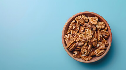 Walnut kernel halves in a wooden bowl Closeup from above on colored background Healthy eating...