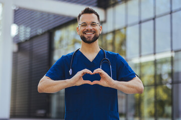 Closeup shot of a medical practitioner making a heart shape with his hands. Cheerful male surgeon...