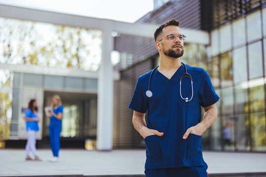 Medical professional working in a hospital. He is dressed in scrubs looking at the camera smiling with a stethoscope around his neck. Young male nurse home caregiver