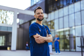Portrait of a young medical practitioner standing with his arms crossed in a hospital. Happy in his Profession. Male nurse with stethoscope standing at clinic. - 787171804