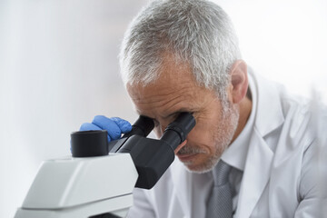 Mature man, microscope and scientist in lab for science innovation, vaccine or antiaging medicine....