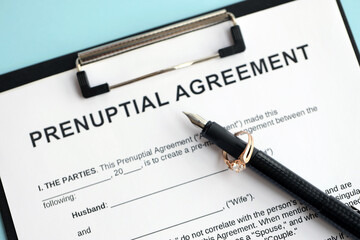 Prenuptial agreement and wedding ring on table. Premarital paperwork process close up
