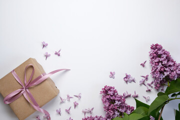 Composition with gift box and lilac flowers on a white background. Flat lay card with copy space.