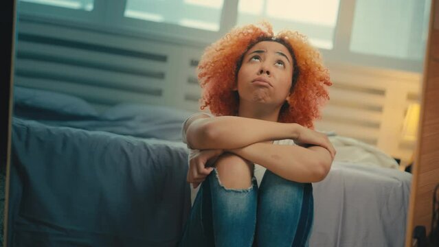 Broken-hearted young woman sitting on the floor near mirror, feeling depressed