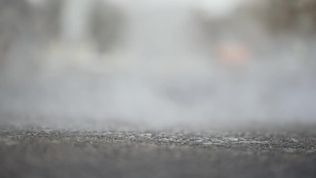 Steam evaporation from new asphalt paving surface at road construction site, slow motion