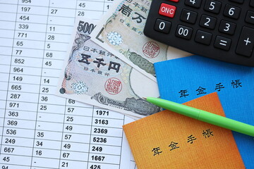Japanese pension insurance booklets on table with yen money bills and calculator on table close up
