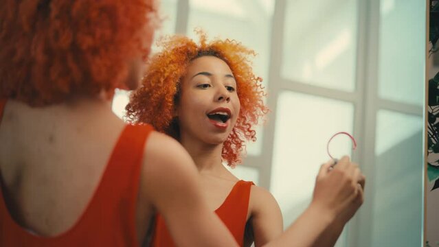 Young woman drawing a heart with red lipstick on mirror, getting ready for party