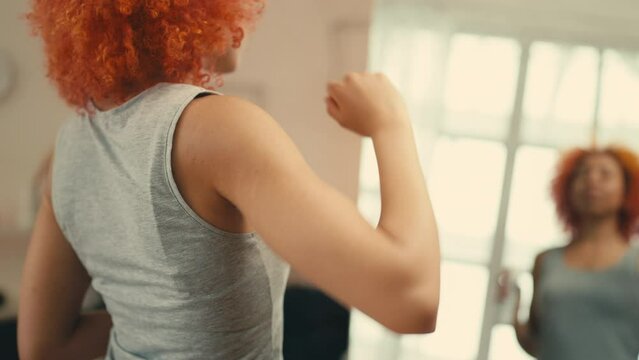 Red-haired woman applying dry antiperspirant spray in front of mirror, skincare
